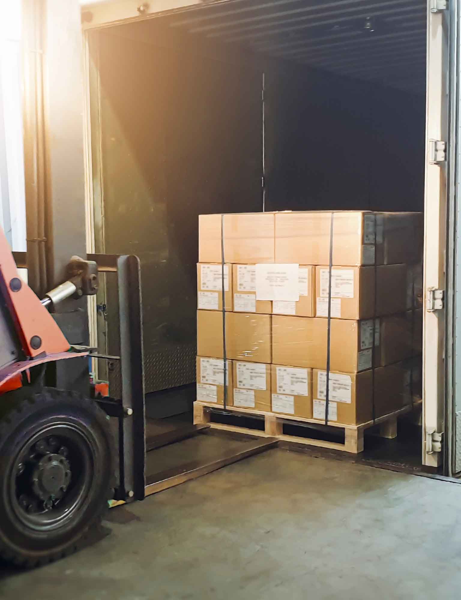 Forklift approaching a pallet of sealed cardboard shipping boxes
